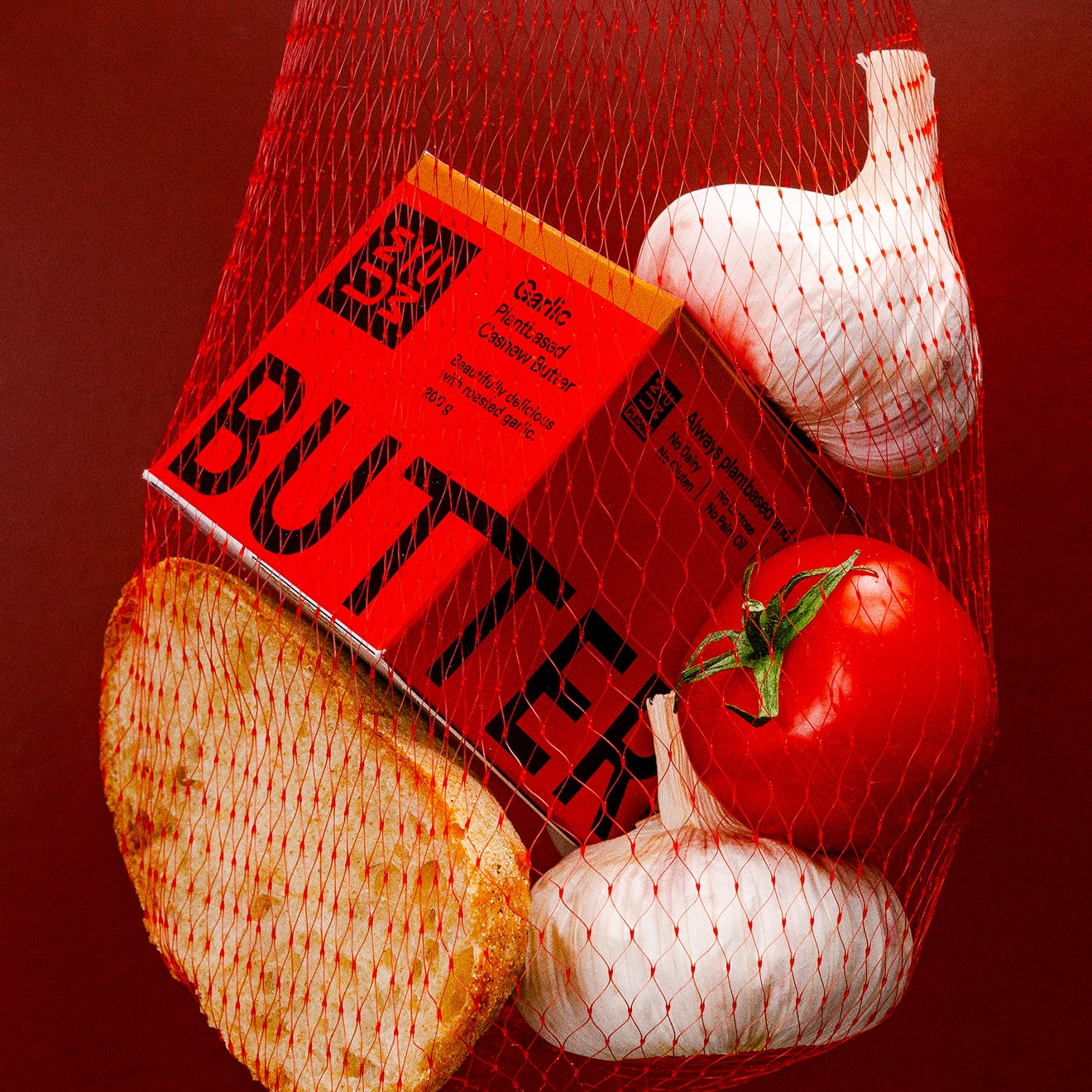 UMYUM Garlic plantbased butter displayed with garlic, tomato, and bread.