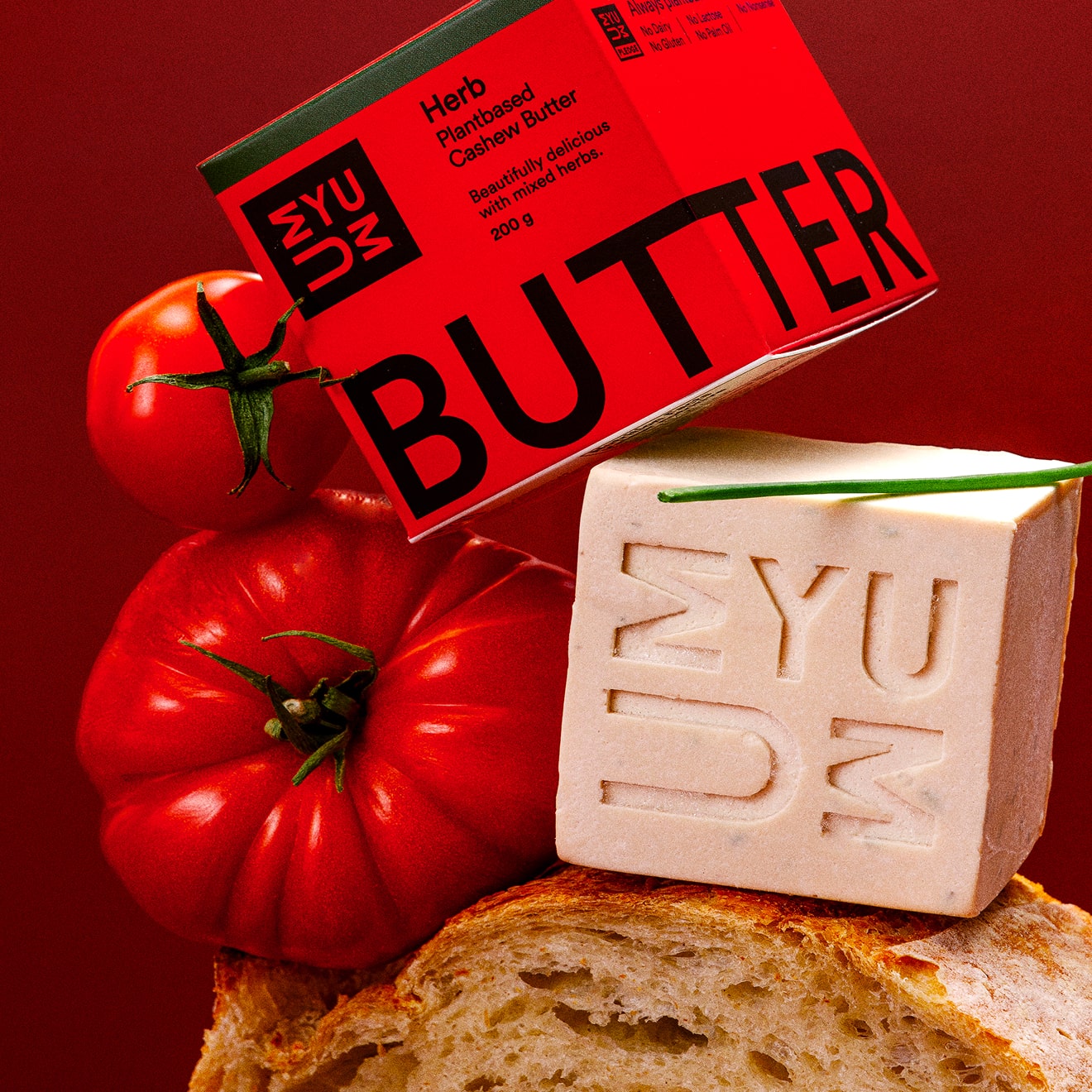 UMYUM Herb plantbased butter displayed with tomatoes and bread.
