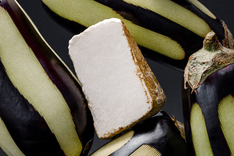 UMYUM Za’atar & Spices plantbased cheese wedge displayed with striped eggplants.
