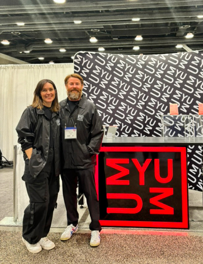 UMYUM founders Baz and Katherine at a trade show exhibition booth.